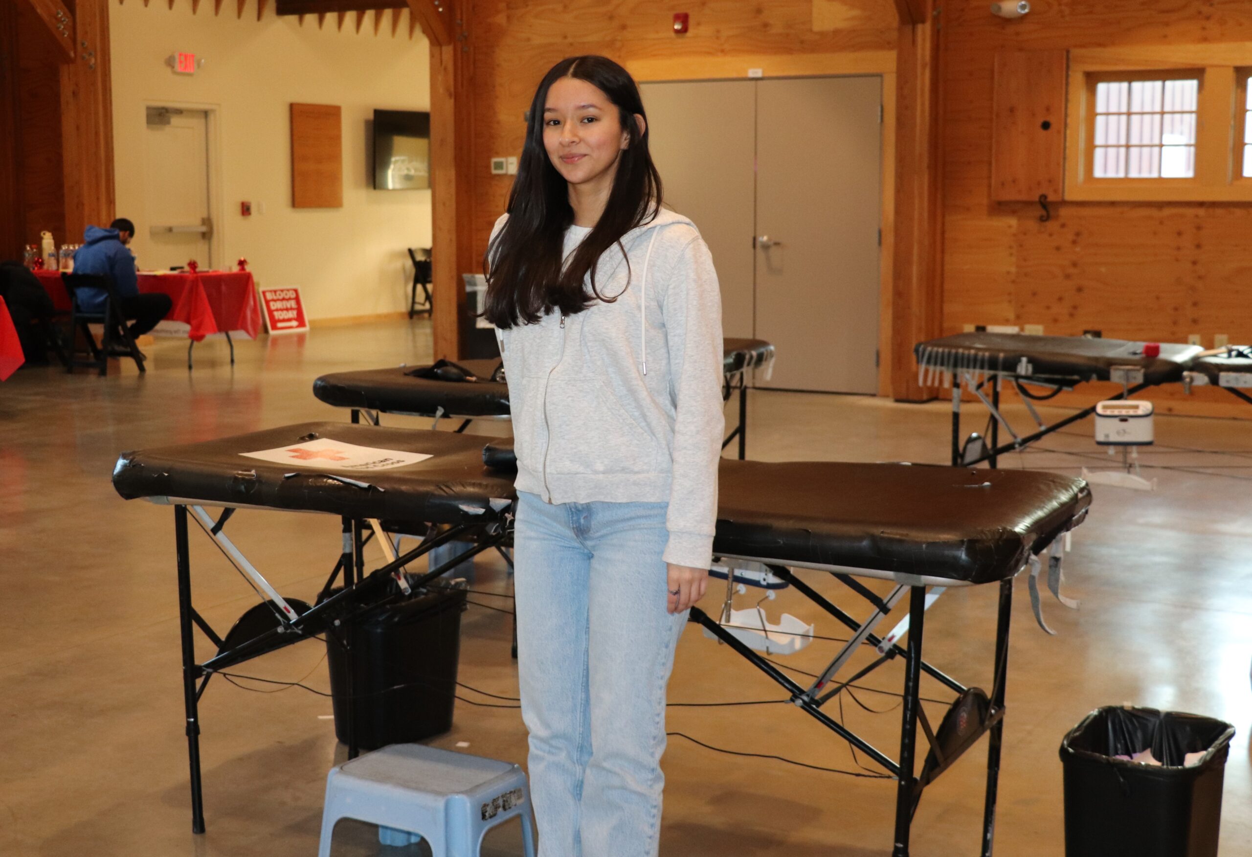 Marissa Luna stands in front of a table used for blood donations at a blood drive.
